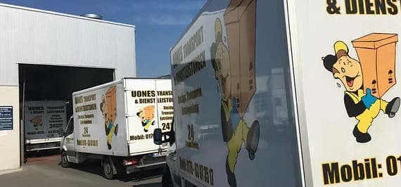 Seitenwand eines UONES-Kofferfahrzeugs mit dem gezeichneten Packer, dahinter weitere Fahrzeuge